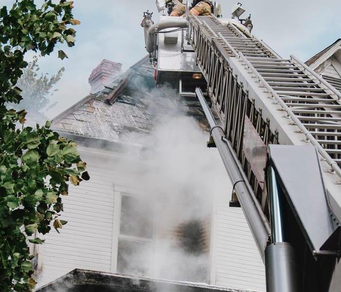 Fire fighter in fire truck putting out a house fire